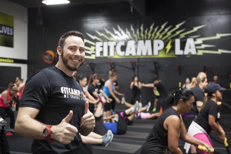 A coach giving a thumbs up while a class trains behind him