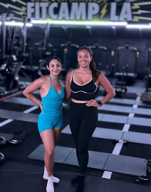 Two Pilates coaches smiling on the studio floor