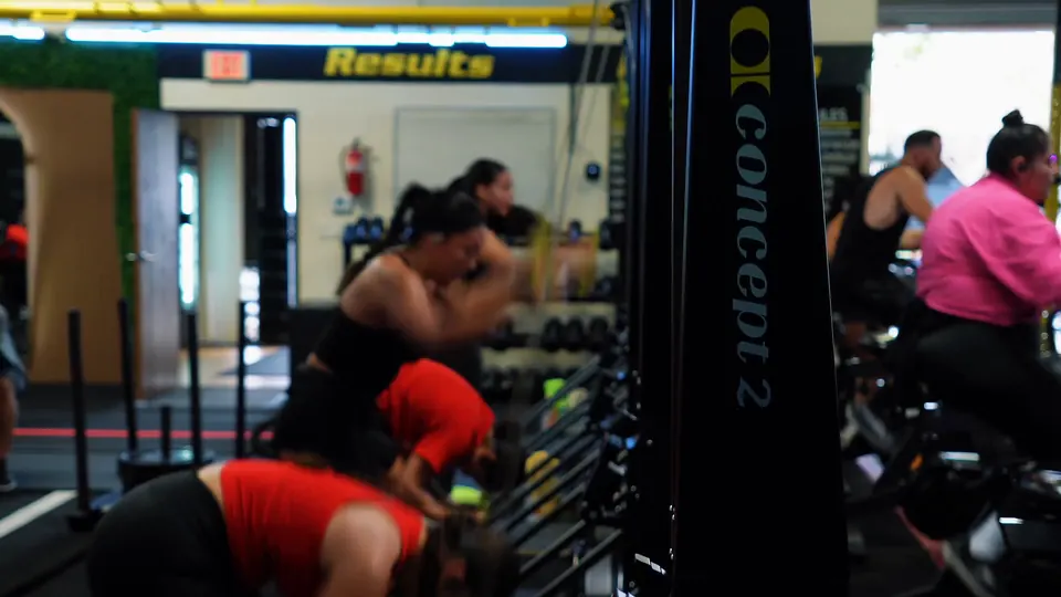 Members training for HYROX on the rowers and sleds