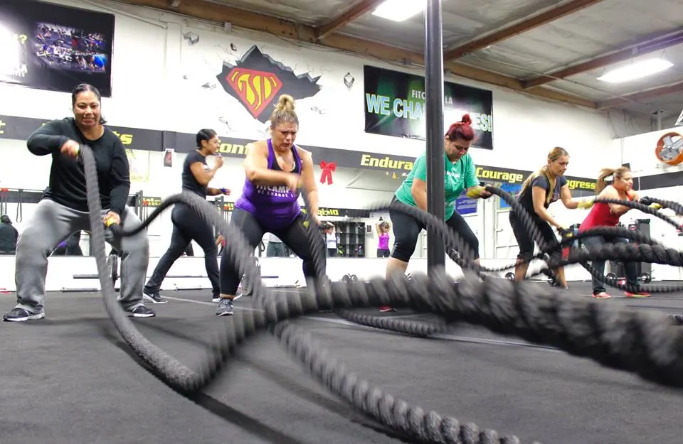 A Fit Camp LA class working battle ropes together on the gym floor